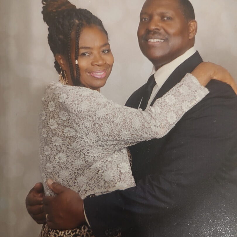 Couple smiling and embracing in formal attire.